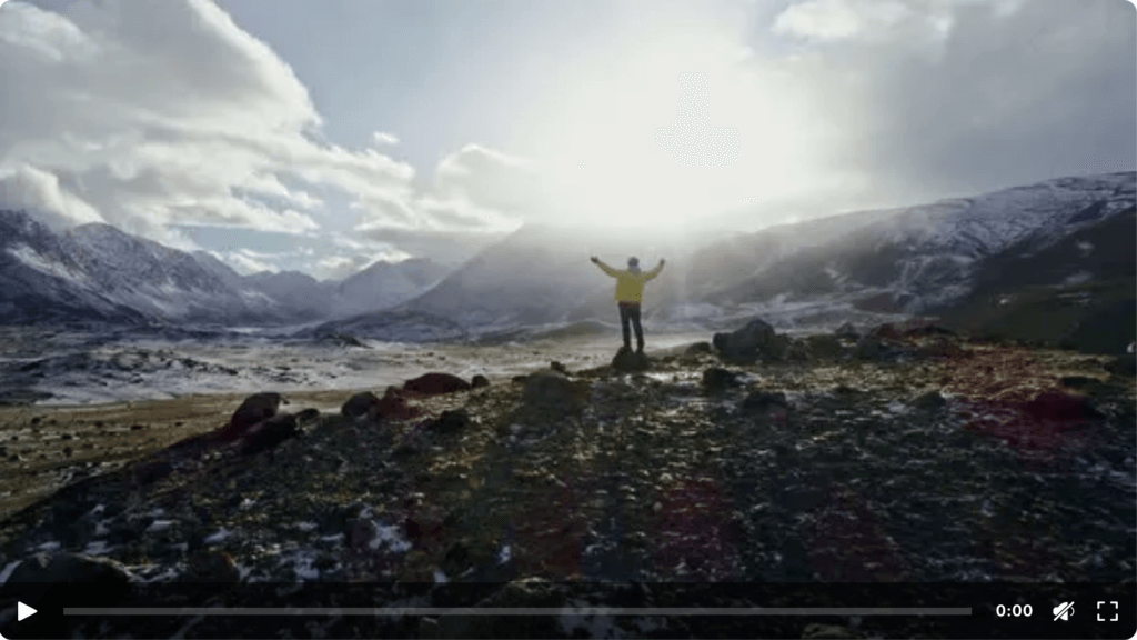 A Man Stands on Top of a Cliff and Enjoys a Beautiful View
