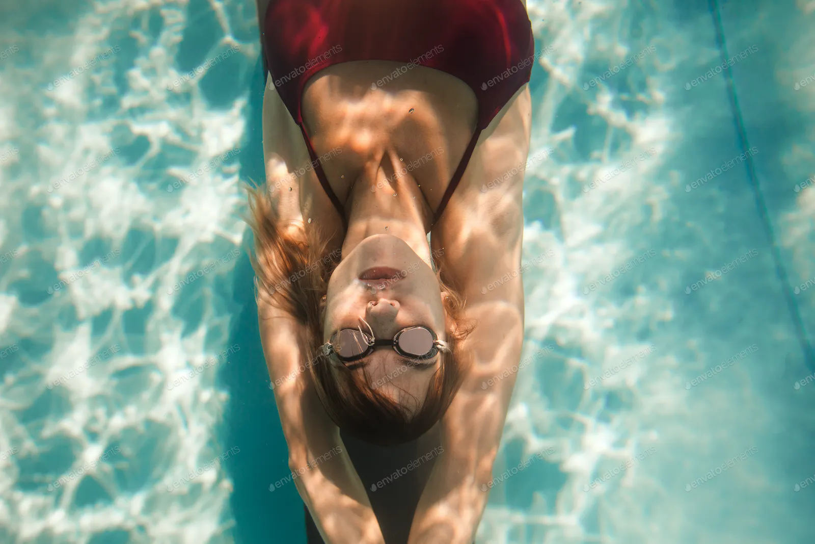 young woman diving in swimming pool, underwater shot

