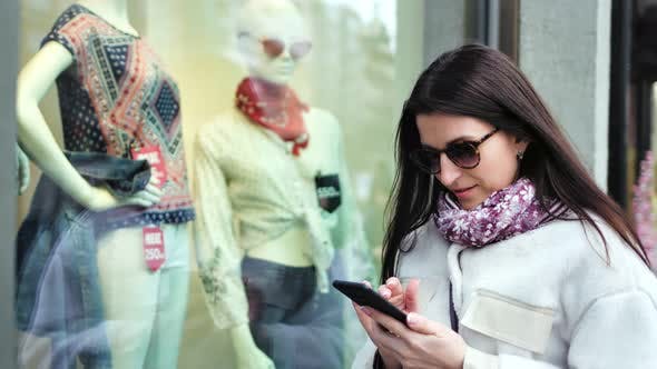 Stylish Shopper Woman Taking Photo of Dummy in Showcase of Shop Fashion Clothes Using Smartphone
